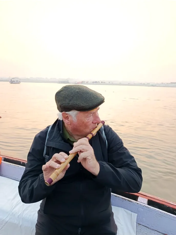 Traveller playing a bamboo flute during a private boat journey on the Ganges in Varanasi