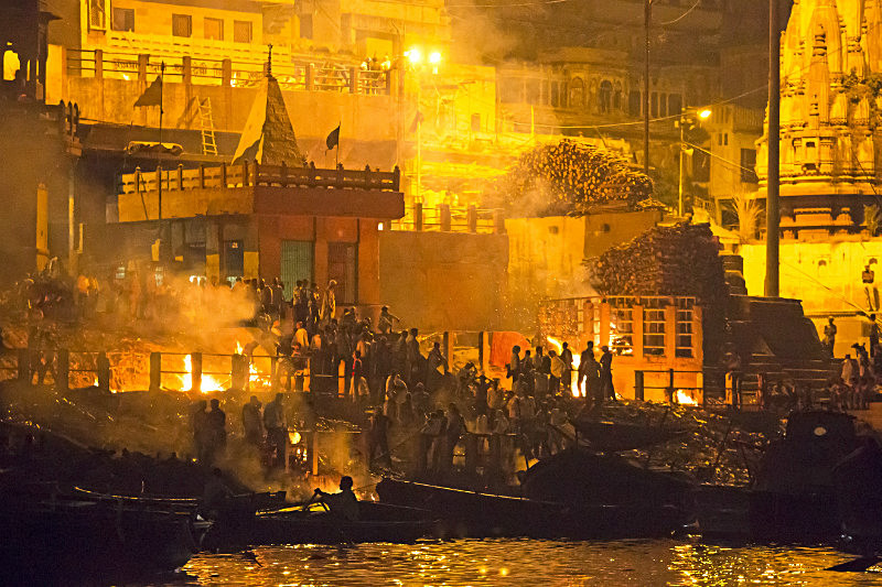 Traveller joining a respectful riverside ritual beside moored wooden boats on the Varanasi ghats
